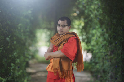 Young man looking away against trees