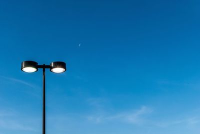 Low angle view of illuminated street light against blue sky