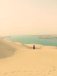 Woman on sand dune against sky