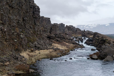 Scenic view of waterfall and mountains against sky