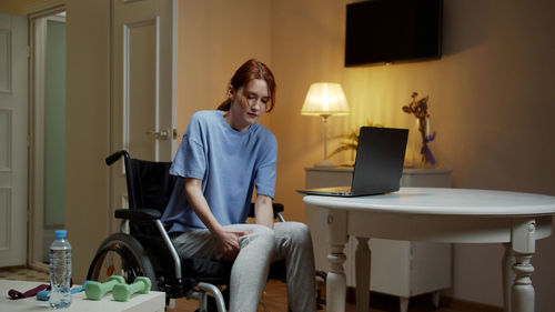 Young woman sitting on wheelchair at home