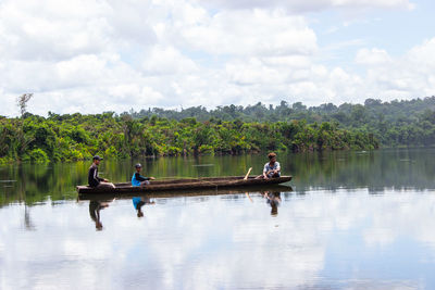 People in boat on lake against sky