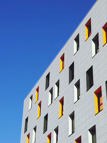 LOW ANGLE VIEW OF MODERN BUILDING AGAINST CLEAR BLUE SKY