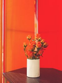 Close-up of vase on table against orange wall