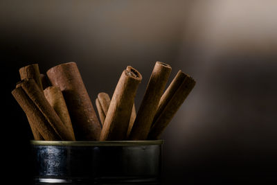 Close-up of cinnamons in metal container against colored background