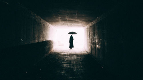 Rear view of silhouette woman walking in tunnel