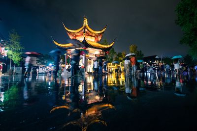 Group of people in illuminated building against sky at night