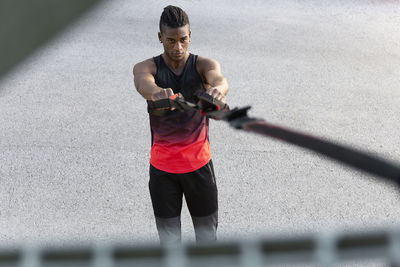 Man exercising with suspension straps outdoors