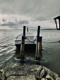 Wooden posts in sea against sky