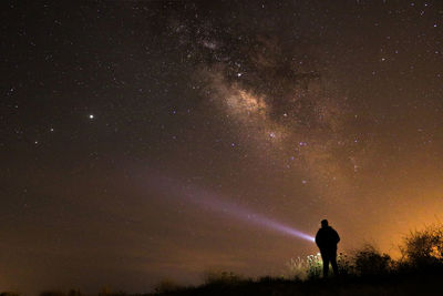 Silhouette man standing against star field at night