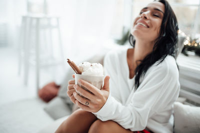 Smiling woman holding hot chocolate sitting at home