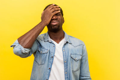 Mid adult man standing against yellow wall