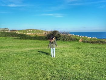 Rear view of man standing on field against sky