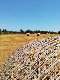 Hay bales on field against clear sky