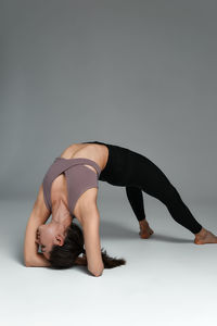 Low section of woman exercising against gray background