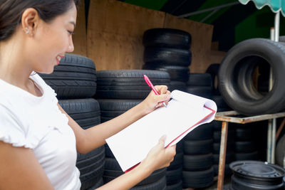 Side view of manager writing on notepad at factory