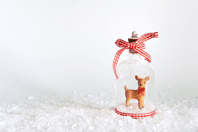 Close-up of figurine on snow against white background