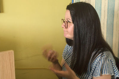 Portrait of young woman against wall at home