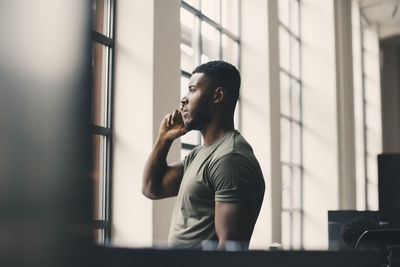 Male entrepreneur talking on mobile phone while looking through window in office