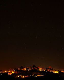 Illuminated city against sky at night