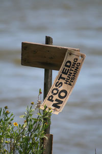 Close-up of text on wood against sea