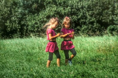 Twins walking against plants at park