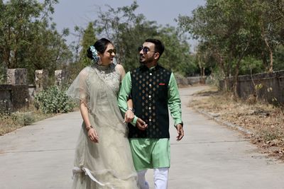 Young couple standing on road against trees