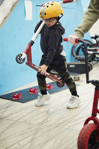 Boy learning how to ride push scooter in indoor skatepark