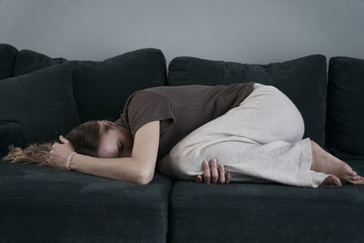 Side view of woman lying on sofa