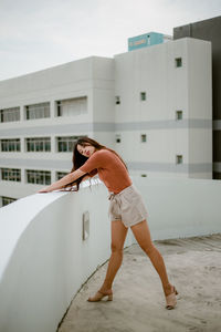 Side view of teenage girl standing against building