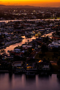 High angle view of townscape by river at sunset
