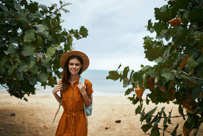 Portrait of young woman standing against plants