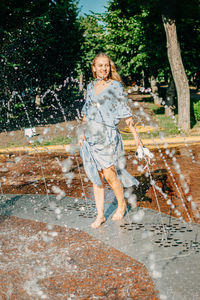 Portrait of smiling young woman standing against trees