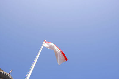 Low angle view of flags against clear blue sky