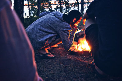 Midsection of man iginiting cigarette near firepit