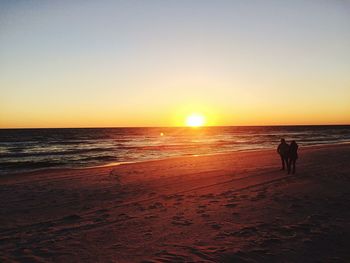 Silhouette man on beach against sky during sunset