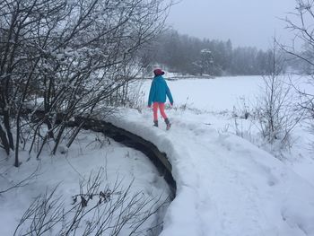 Rear view of woman walking on snow covered landscape