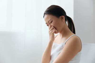 Side view of young woman looking away while sitting at home