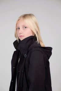 Portrait of teenage girl wearing winter coat against white background