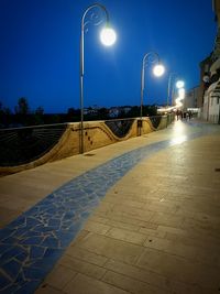 Illuminated street light against sky at night
