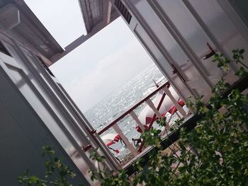 Buildings by sea against sky seen through window