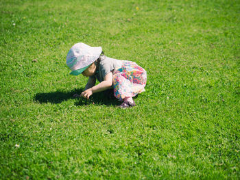 Side view of girl kneeling on grassy field