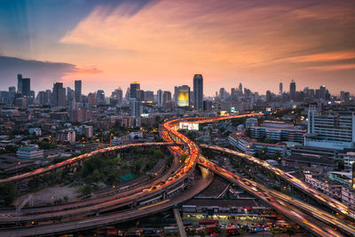 High angle view of illuminated multiple lane highway and buildings in city at dusk