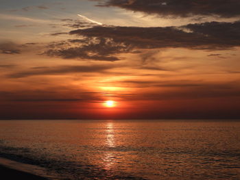 Scenic view of sea against dramatic sky during sunset