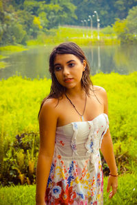 Beautiful young woman looking away while standing on grassy field at park