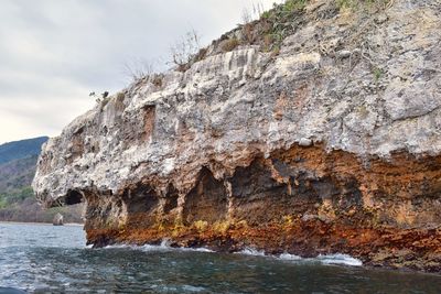 Rock formations by sea against sky