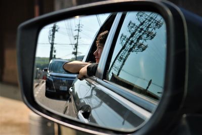Reflection of teenage boy seen in side-view mirror