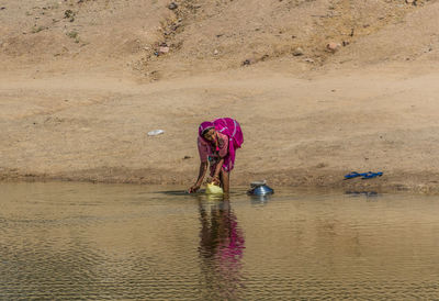 Rear view of man working in lake