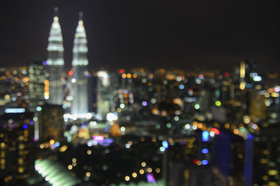 Defocused image of illuminated city against sky at night