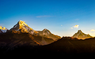 Scenic view of snowcapped mountains against blue sky